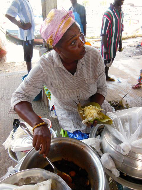 This woman sells street food by the Harbour. The dish she assembles is rice and noodles piled onto a banana leaf, and then spooned with a spicy, shrimp-based red sauce that often has boiled eggs and bits of meat cooked in it.